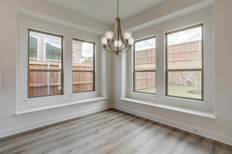 Unfurnished dining area with light hardwood / wood-style floors, a wealth of natural light, and an inviting chandelier