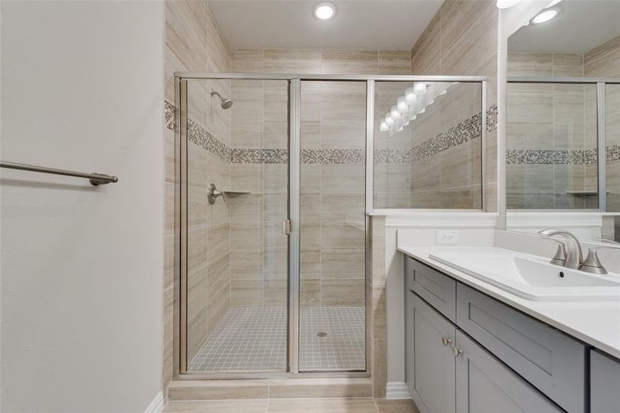 Bathroom featuring tile patterned flooring, a shower with shower door, and vanity