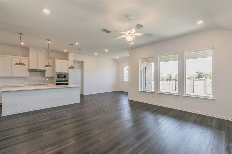 Kitchen featuring hanging light fixtures, dark wood-type flooring, stainless steel appliances, and white cabinets