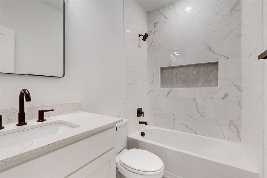 Full bathroom featuring tiled shower / bath combo, vanity, and toilet