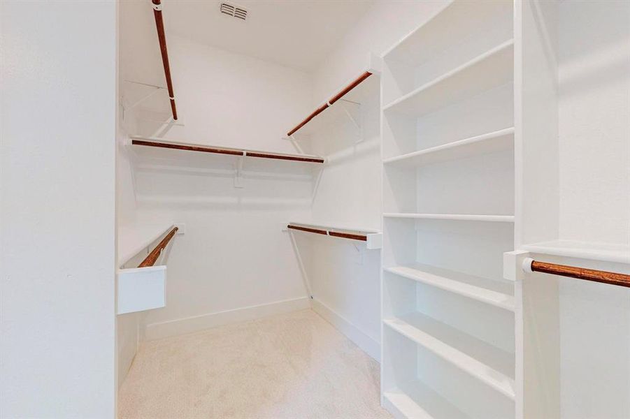 Walk in closet with light colored carpet