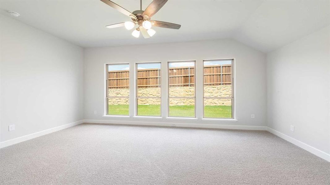 Carpeted empty room with lofted ceiling and ceiling fan