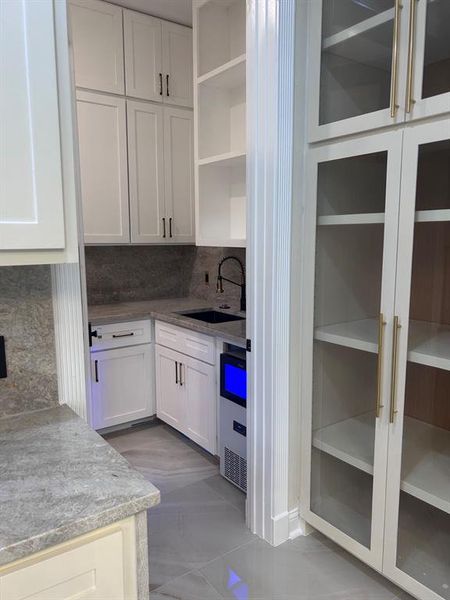 Butler pantry with double entrance has sink and ice maker.