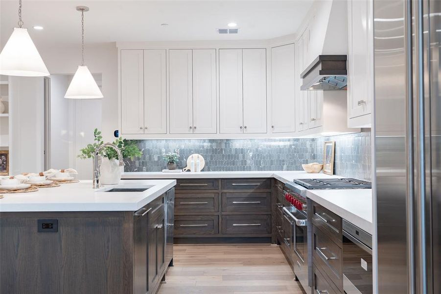 Kitchen with Sub Zero fridge, Wolf range stove, marble backsplash, 2 inch thick quartz countertops, and an island with sink.