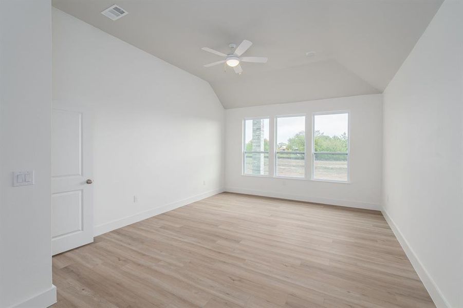 Spare room featuring ceiling fan, vaulted ceiling, and light hardwood / wood-style flooring