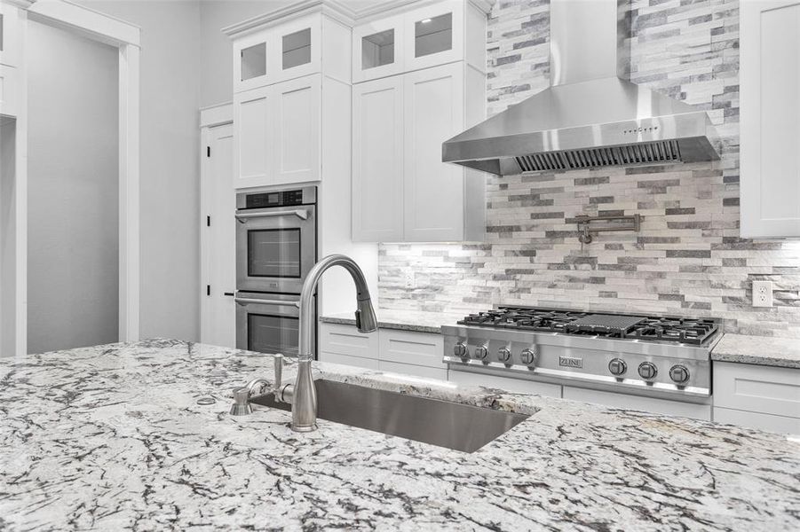 This Kitchen is equipped and/or has space for every modern convenience w/ a large island, loads of storage & cabinets double-ovens; a 6-burner gas range w/ a griddle, a Delta pot-filler, commercial hood & tile backsplash that runs to the ceiling.