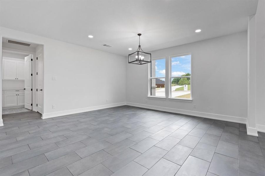 Spare room featuring an inviting chandelier and tile patterned floors