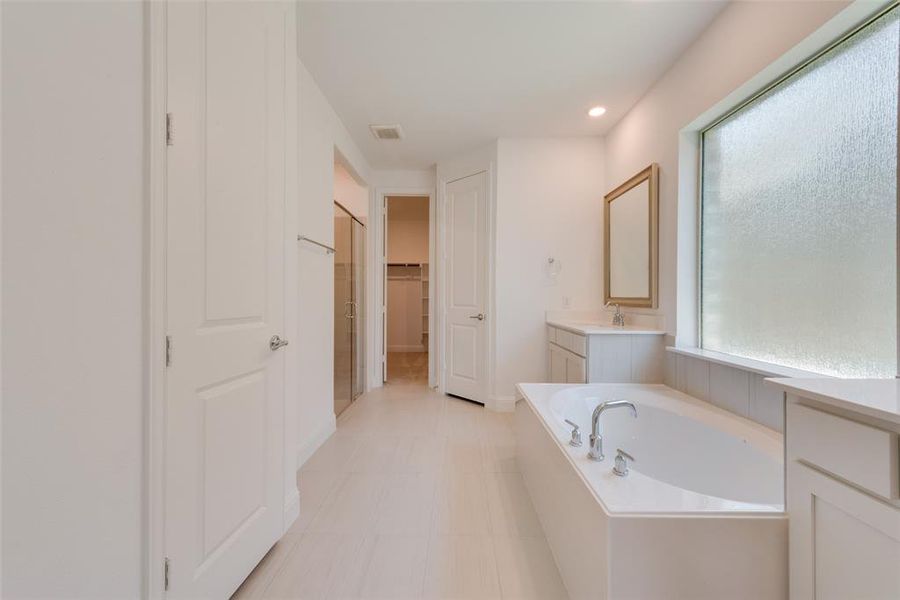 Bathroom with plenty of natural light, a bathing tub, vanity, and tile patterned flooring