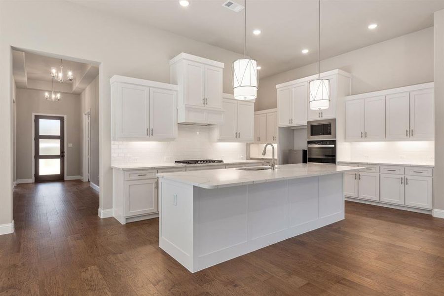 Kitchen with a kitchen island with sink, dark wood-type flooring, white cabinets, built in microwave, and black oven