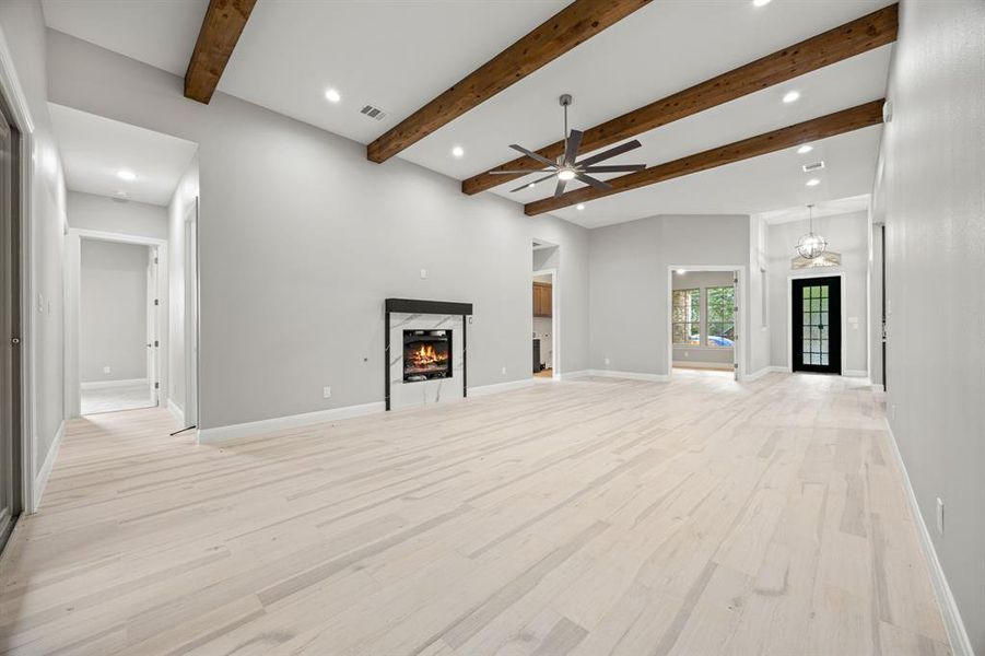 living room  / wood-tilestyle floors, beam ceiling, ceiling fan, and a high end fireplace