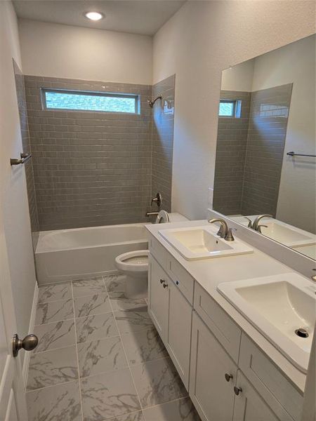 Full bathroom with toilet, vanity, and tiled shower / bath combo