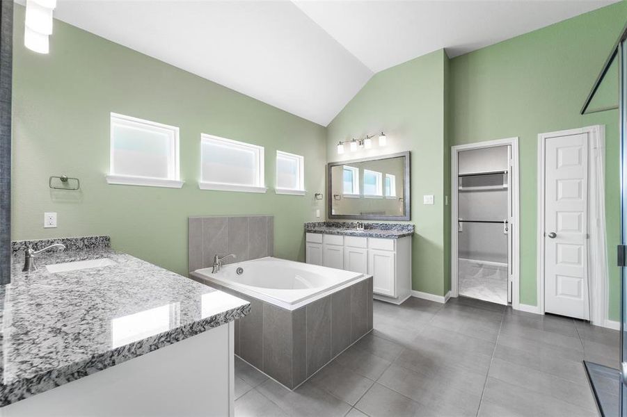 Spacious primary bath has separate vanities, soaking tub, large format 12x24 tiles, high ceilings and plenty of natural light