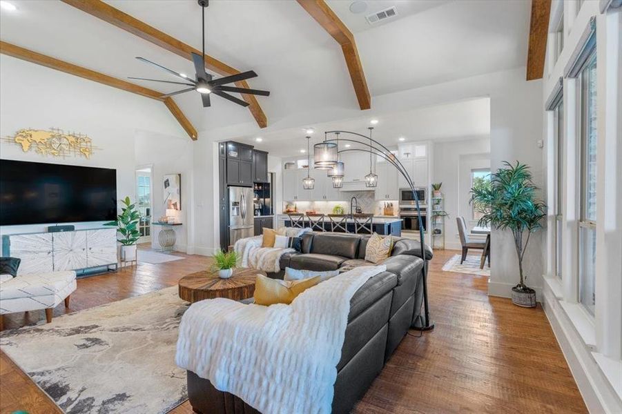 Living room featuring high vaulted ceiling, wood-type flooring, ceiling fan, and beamed ceiling