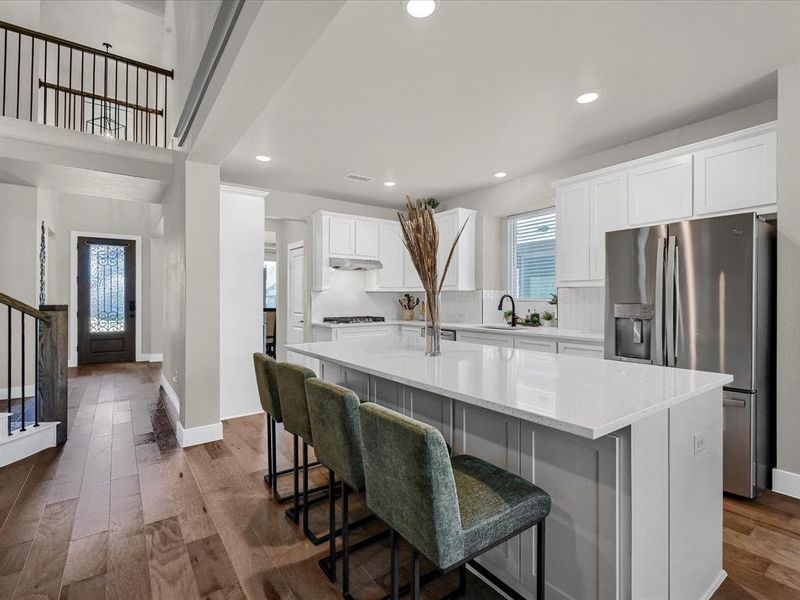 Kitchen featuring stainless steel fridge, a kitchen island, a kitchen breakfast bar, white cabinetry, and dark hardwood / wood-style floors