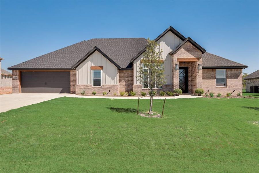 View of front facade featuring a front yard and a garage