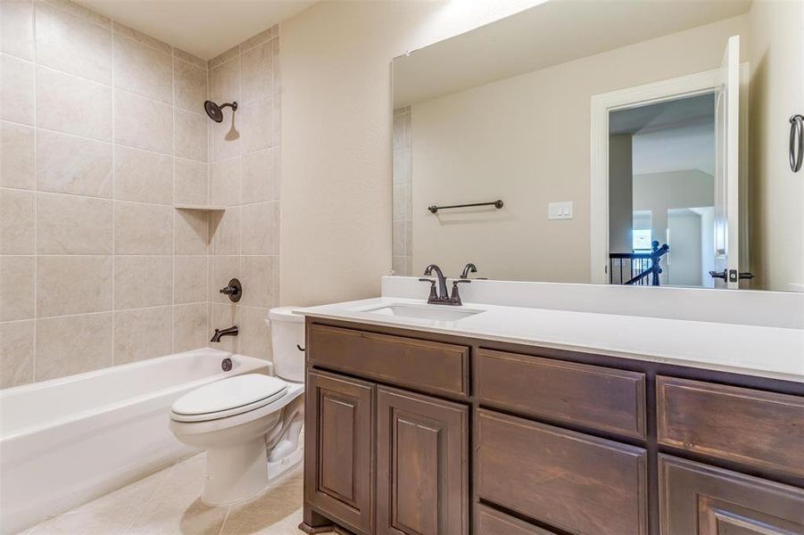 Full bathroom with toilet, tiled shower / bath combo, vanity, and tile patterned floors