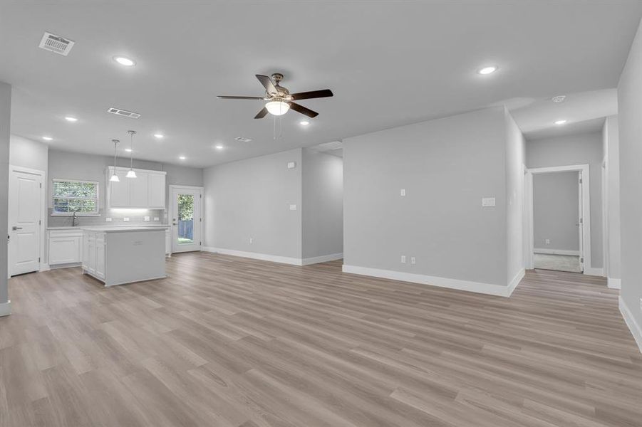 Unfurnished living room featuring ceiling fan, sink, and light hardwood / wood-style floors