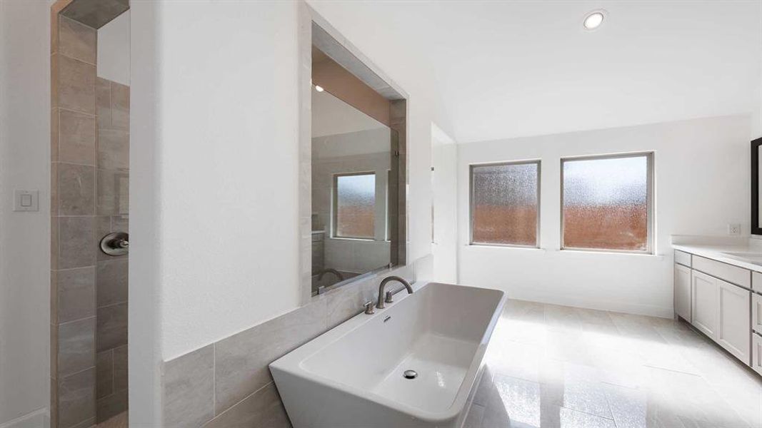 Bathroom featuring vanity, a tile shower, and tile walls