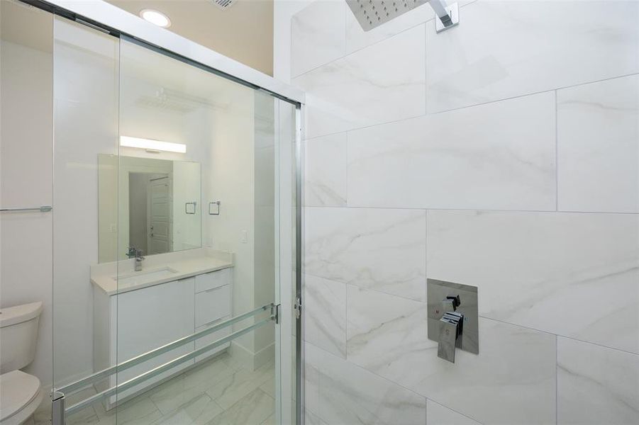 Bathroom featuring tile floors, a shower with shower door, toilet, and vanity