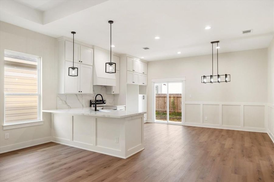 The kitchen and dining areas seamlessly combine in this open-concept space. Pendant lights at the kitchen peninsula add to the already well-lit home, as well as offers extra seating for your guests or little ones!