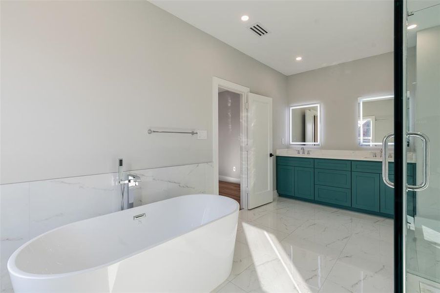 Bathroom featuring shower with separate bathtub, tile walls, and vanity