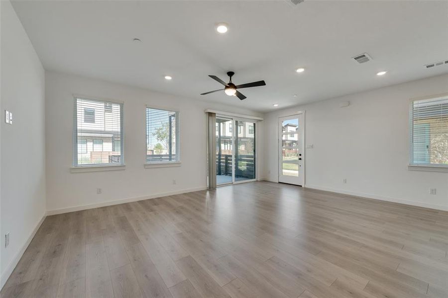 Spare room featuring a wealth of natural light, ceiling fan, and light hardwood / wood-style floors