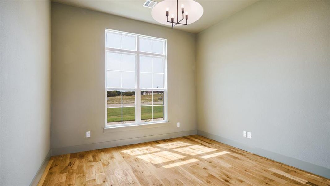 Empty room with an inviting chandelier and light wood-type flooring