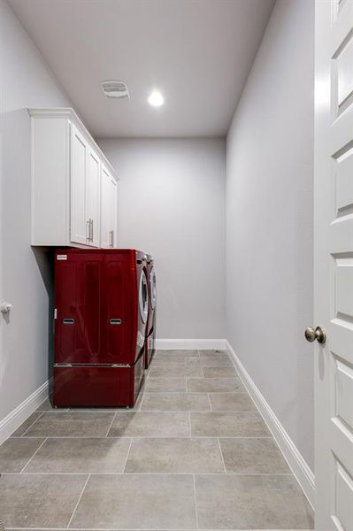 Clothes washing area featuring washer and dryer and cabinets