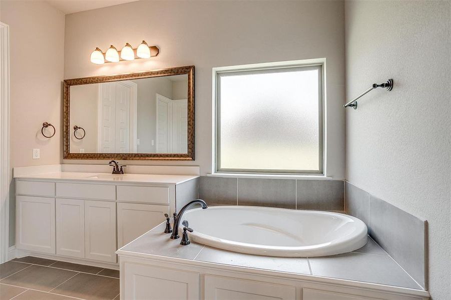 Bathroom featuring vanity, a washtub, and tile patterned floors