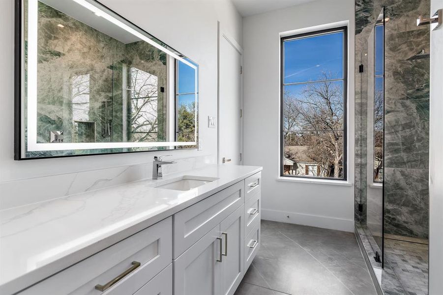 Bathroom featuring vanity, a healthy amount of sunlight, and a shower with shower door