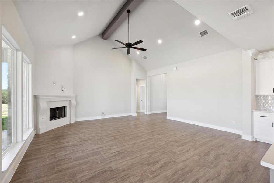 Unfurnished living room featuring high vaulted ceiling, ceiling fan, beamed ceiling, and dark hardwood / wood-style flooring