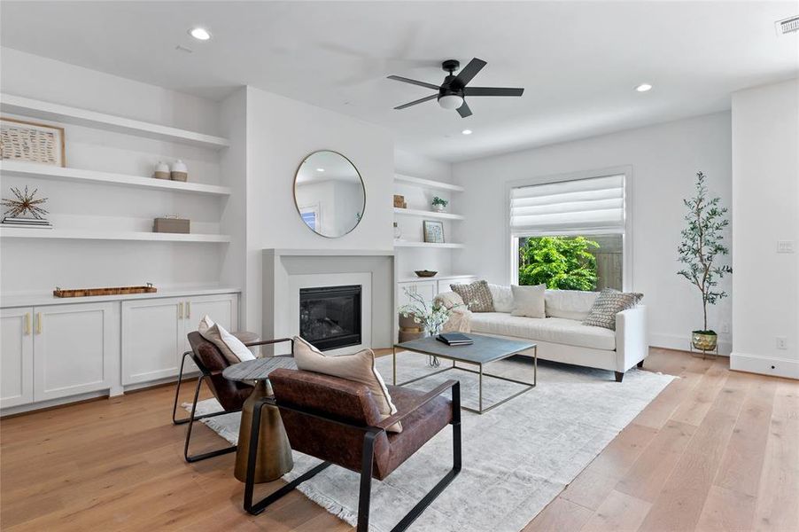 Discover the charm of this sunlit living space, boasting a sophisticated Madrid-style cast stone fireplace, custom-built shelving, and generous storage solutions.