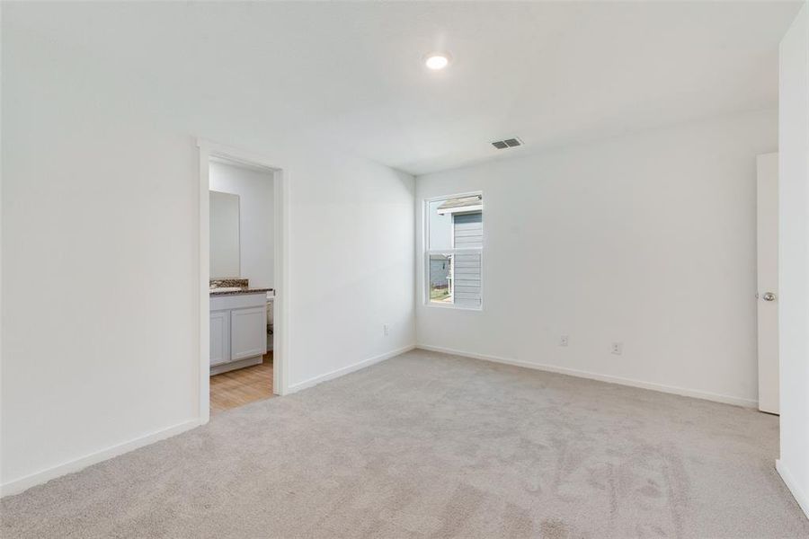 Unfurnished bedroom featuring connected bathroom and light colored carpet