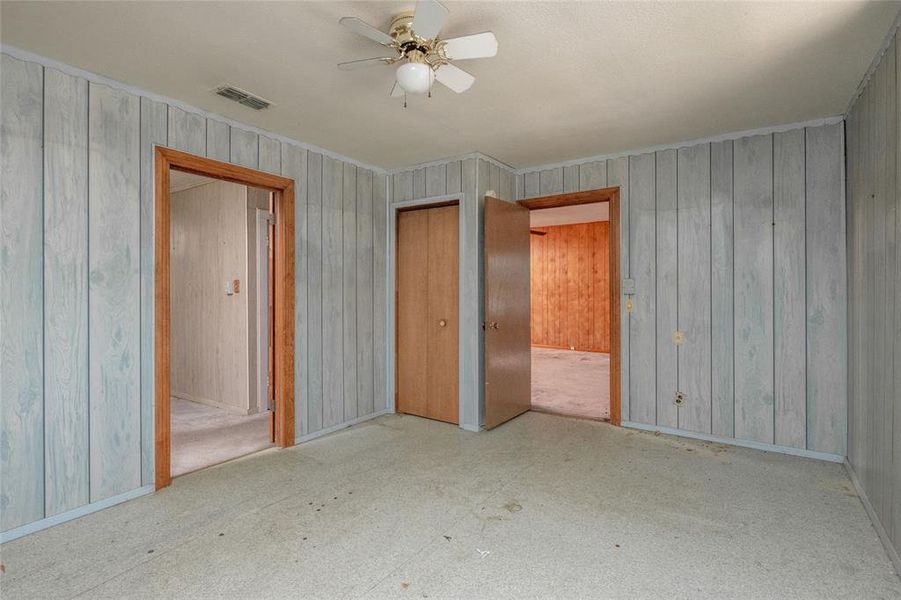 Unfurnished bedroom featuring ceiling fan and wood walls