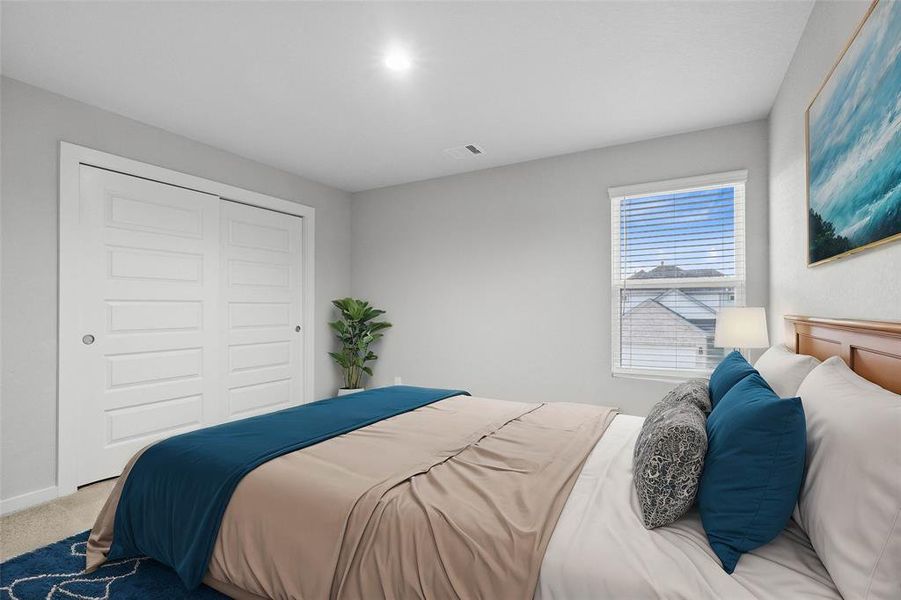 This secondary bedroom features high ceilings, recessed lighting, custom paint, plush carpet, ample closet space, and a large window with privacy blinds!