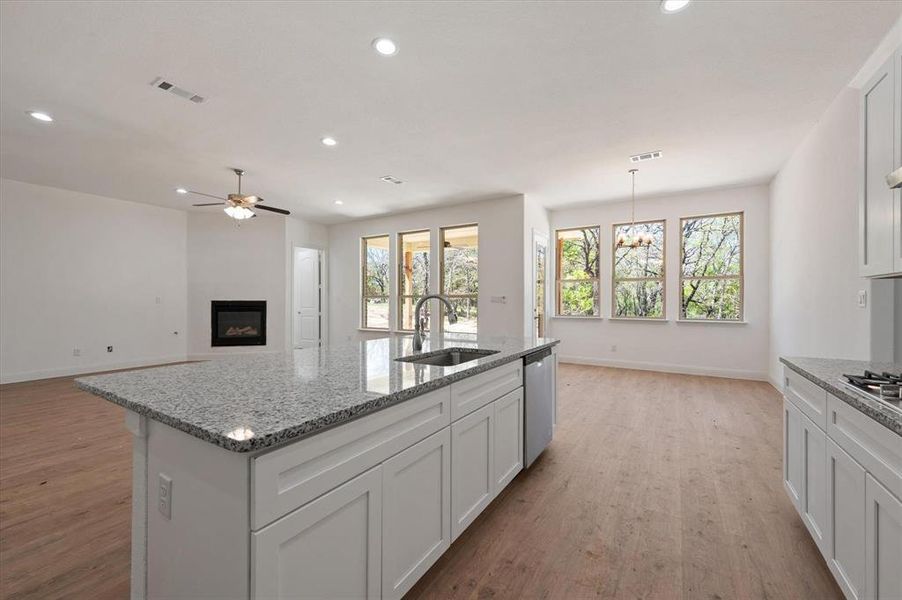 Kitchen with a kitchen island with sink, sink, white cabinets, light wood-type flooring, and appliances with stainless steel finishes