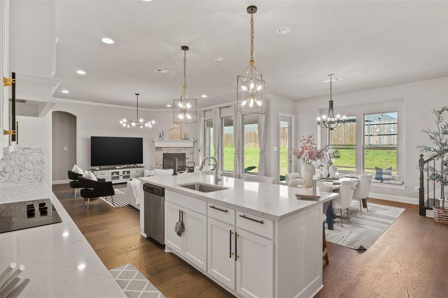 Kitchen featuring sink, a stone fireplace, plenty of natural light, white cabinetry, and dishwasher