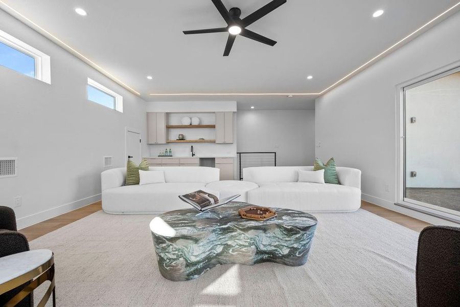 Living room with ceiling fan, sink, and light wood-type flooring