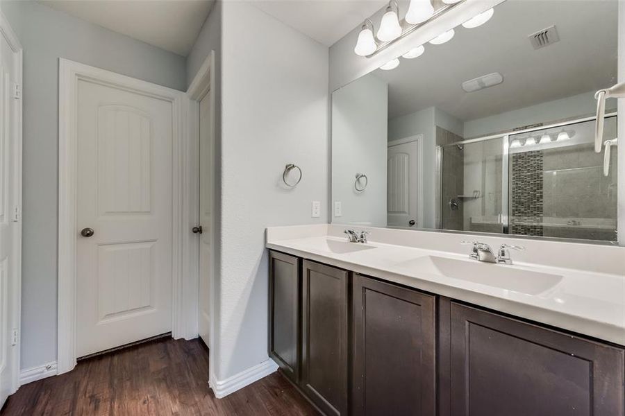 Bathroom featuring a shower with door, dual bowl vanity, and hardwood / wood-style floors