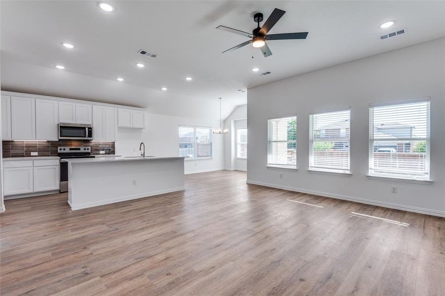 Kitchen with a center island with sink, white cabinetry, appliances with stainless steel finishes, and light hardwood / wood-style floors