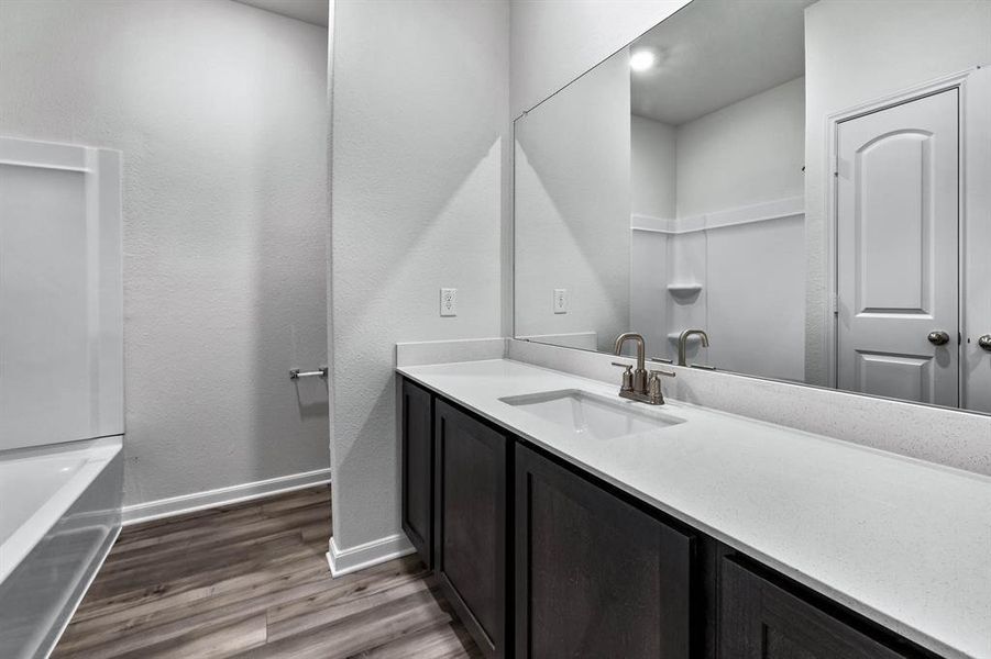 Bathroom featuring a bath to relax in, vanity with extensive cabinet space, and hardwood / wood-style flooring