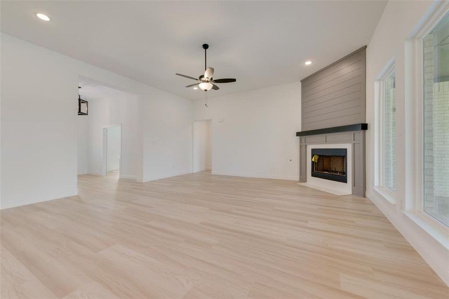 Unfurnished living room with ceiling fan, light hardwood / wood-style flooring, and a large fireplace