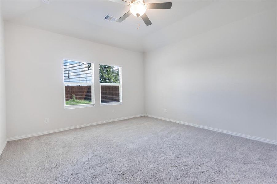 Empty room featuring carpet flooring, lofted ceiling, and ceiling fan
