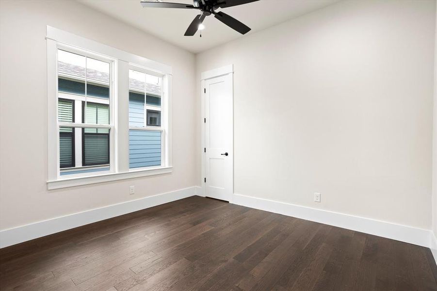 Unfurnished room with dark wood-type flooring and ceiling fan