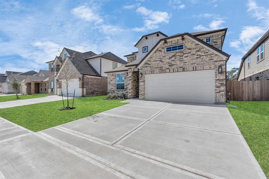 Home showcases a convenient 2-car garage paired with a spacious driveway, providing ample room for parking. Sample photo of completed home with similar floor plan. As built color and selections may vary.