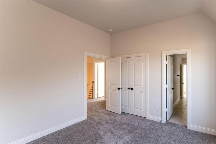 Unfurnished bedroom featuring light carpet, vaulted ceiling, and a closet