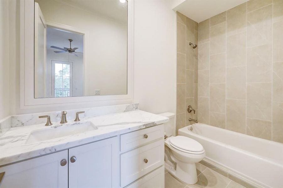 This secondary ensuite bath features a framed mirror, tiled shower and marble counter.