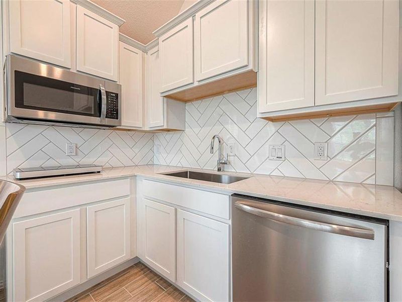 This kitchen features sleek stainless steel appliances, crisp white cabinets, and granite countertops for a timeless and sophisticated look.