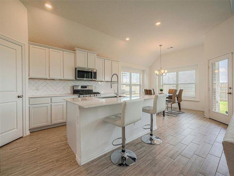 This kitchen features timeless white cabinets, stainless steel appliances, and a warm wood floor. The simple design creates a clean and inviting space.