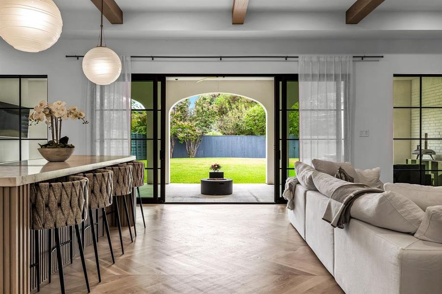 Doorway to outside featuring beamed ceiling and light parquet flooring